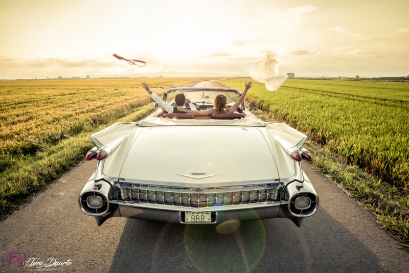 novios en Cadillac hacia el atardecer